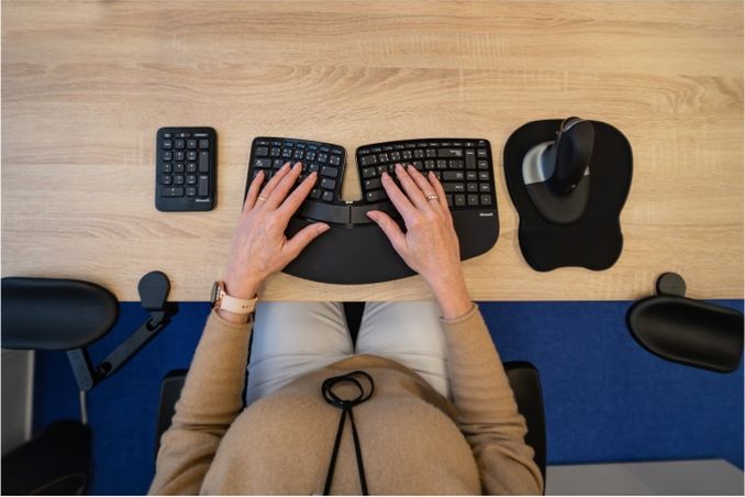 Žena s rukama položenýma na ergonomické klávesnici