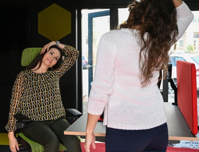 Dvě ženy provádějící fyziotarepeutické cviky v kancelářském prostředí