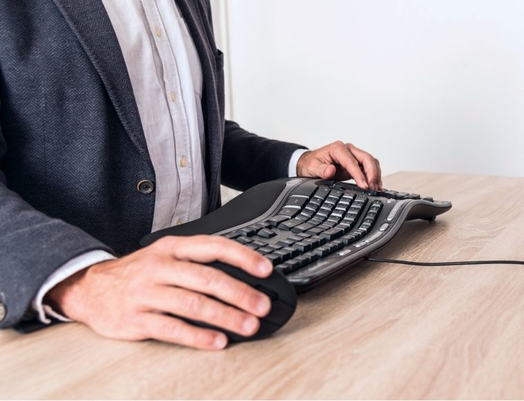 Člověk pracující s ergonomickou klávesnicí a vertikální myší